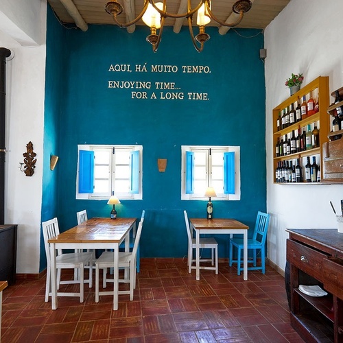 una habitación con mesas y sillas y un letrero en la pared que dice aqui ha muito tempo