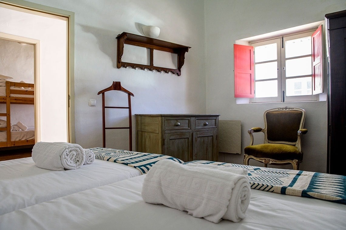 una habitación con dos camas y una ventana con persianas rojas