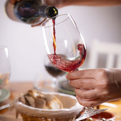 a person is pouring red wine into a glass