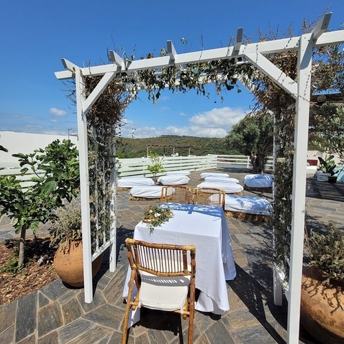 una mesa y sillas están bajo un arco blanco