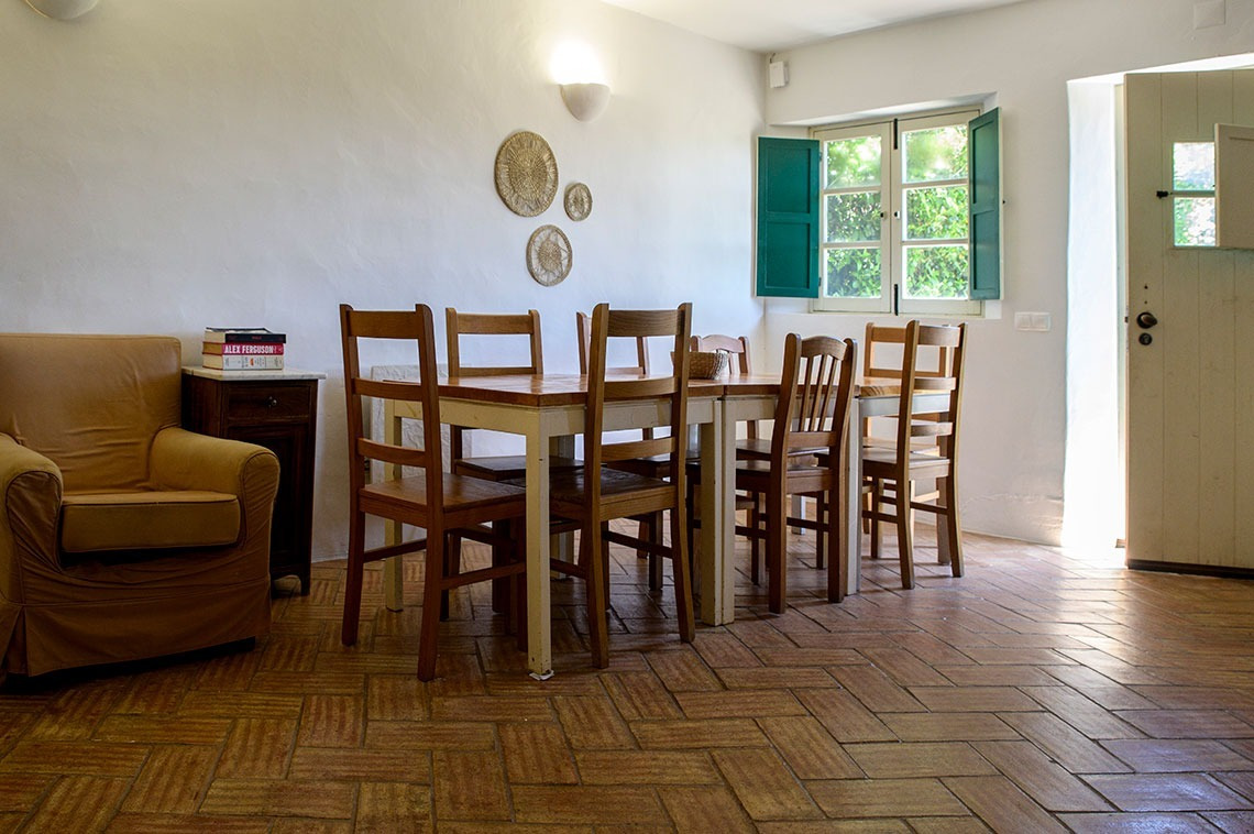 Aconchegante sala de jantar na Aldeia da Pedralva com móveis de madeira, decoração rústica e janela luminosa.