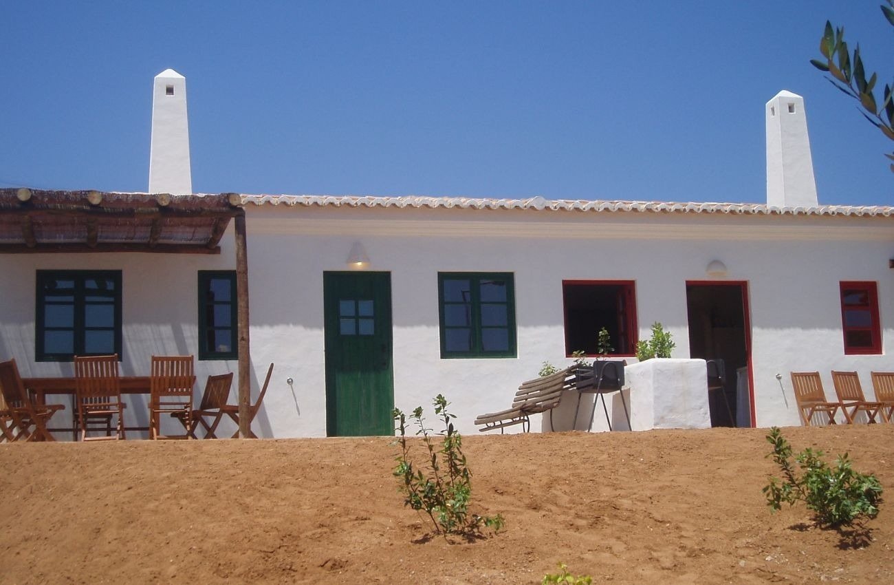 uma casa branca com portas verdes e janelas vermelhas