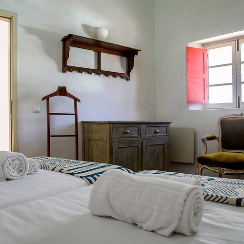Aldeia da Pedralva hotel room with bunk beds, dresser, and a vintage chair.