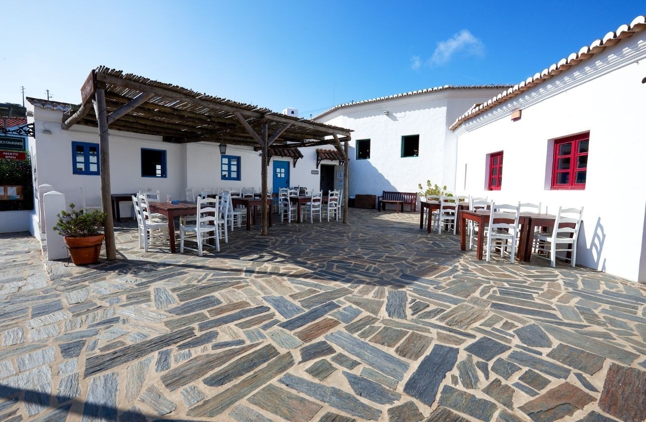 un patio con mesas y sillas frente a un edificio blanco