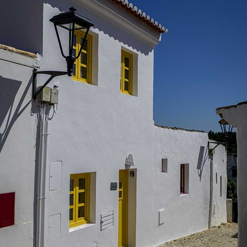 Charming white houses with yellow accents in Aldeia da Pedralva.