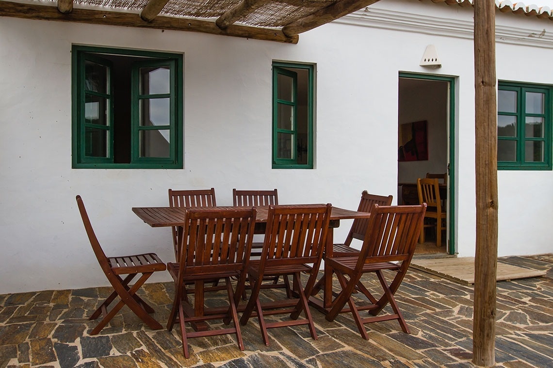 una mesa y sillas de madera frente a una casa blanca