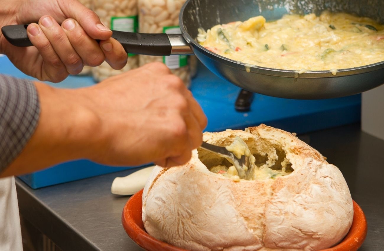 a person is dipping a piece of bread into a bowl of food