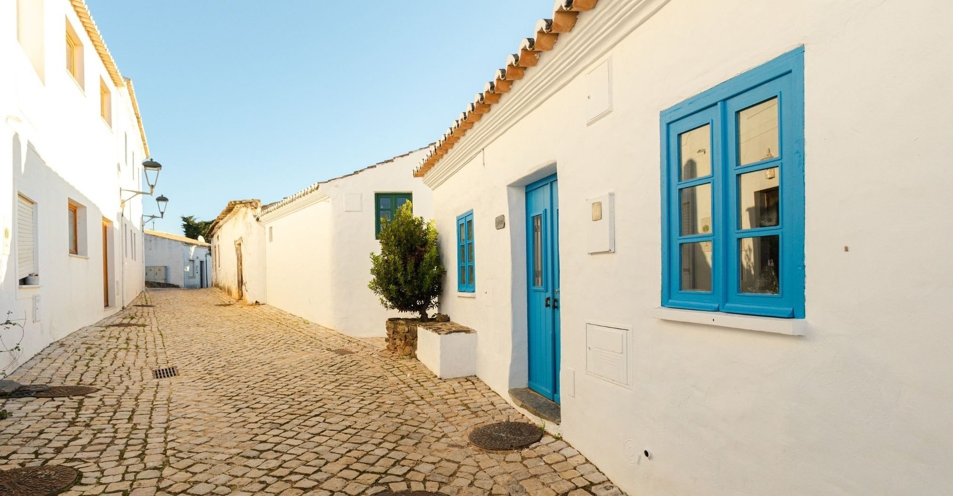 uma rua estreita com casas brancas e janelas azuis