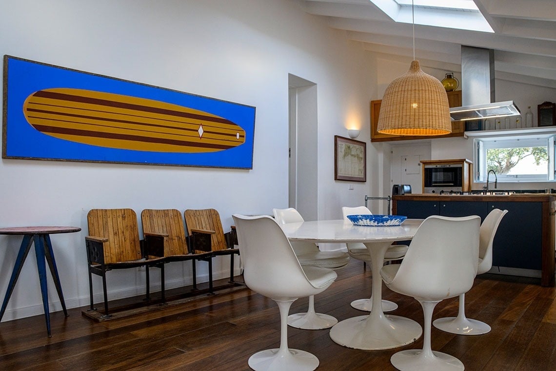 un comedor con una mesa y sillas y una pintura de una tabla de surf en la pared