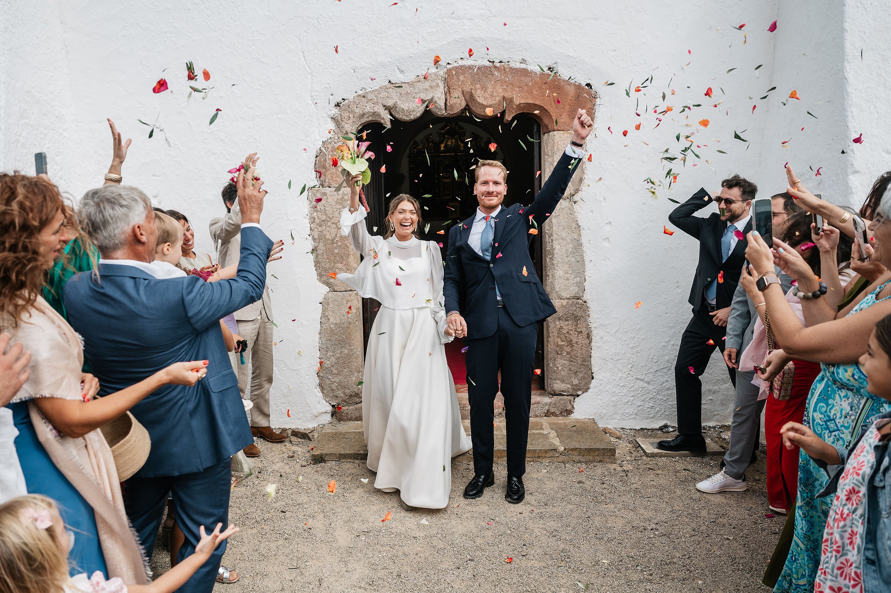 Casal recém-casado comemorando com pétalas de flores na frente de um hotel. Aldeia da Pedralva