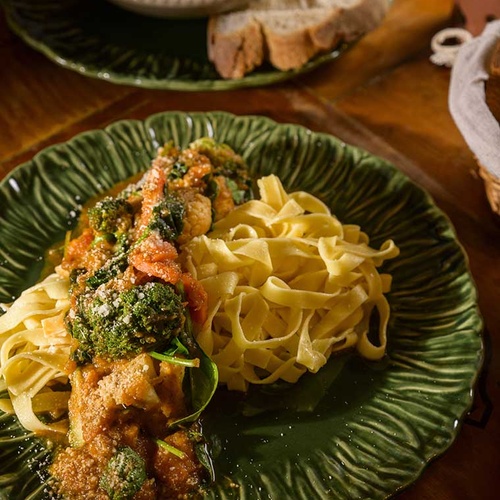 Delicious pasta dish with broccoli and tomato sauce, served on a green plate at Aldeia da Pedralva.