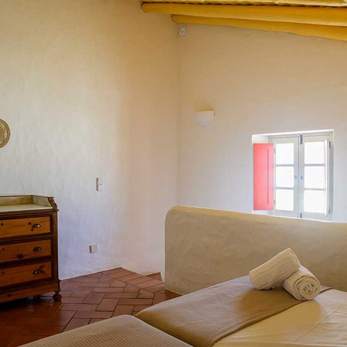 Cozy bedroom in Aldeia da Pedralva with rustic dresser and bright window.