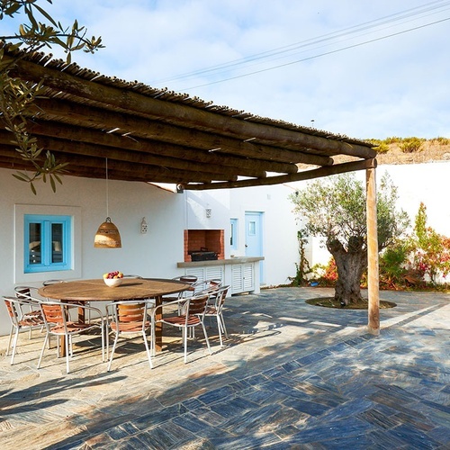 un patio con una mesa y sillas y una pergola de madera