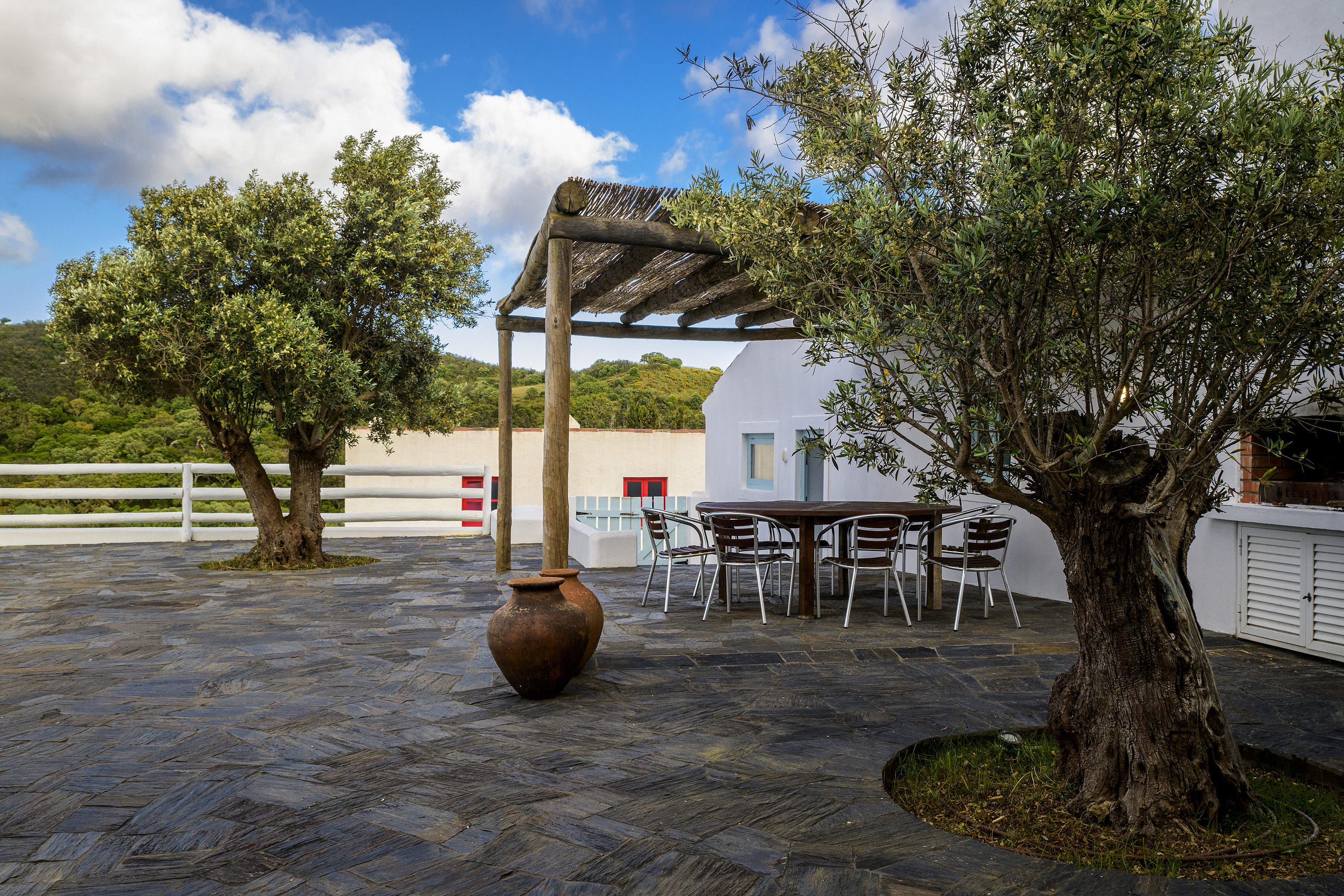 Terraza con mesa, sillas y olivo en hotel Aldeia da Pedralva, con vistas al campo.