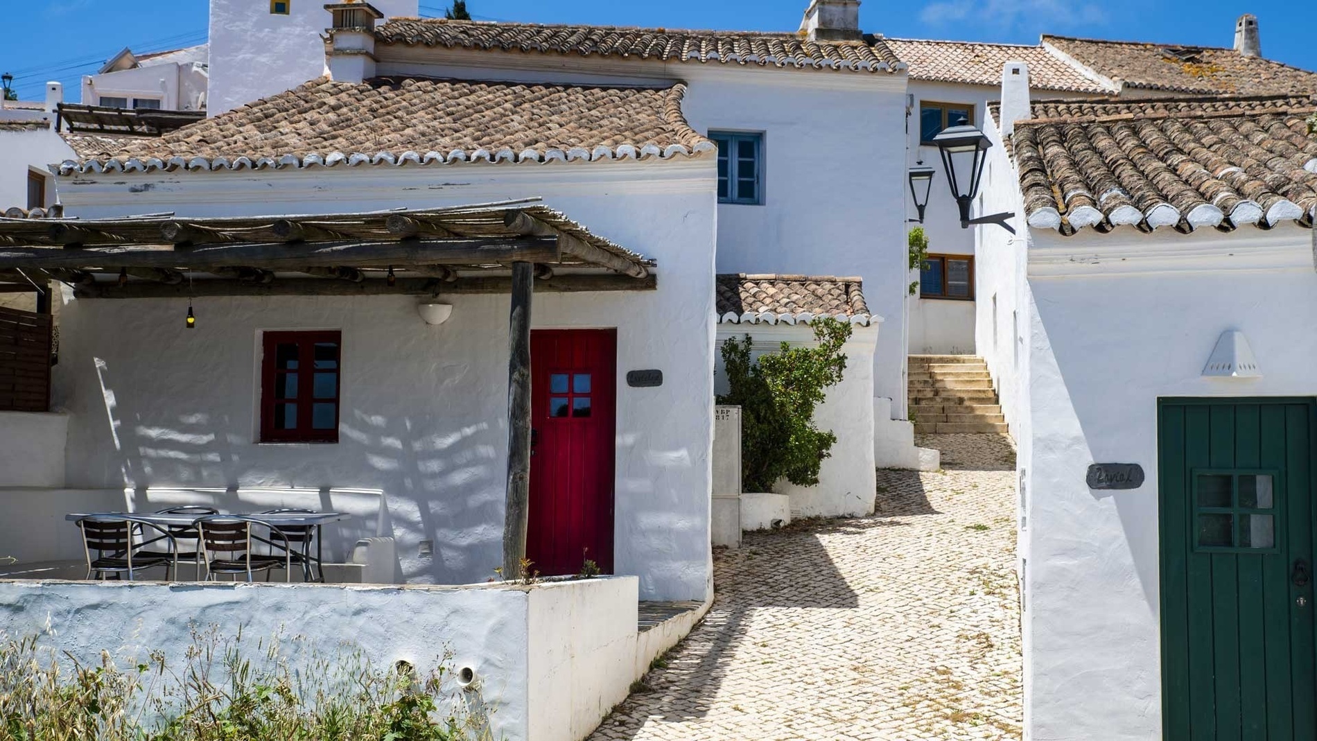 a white house with a red door and a green door
