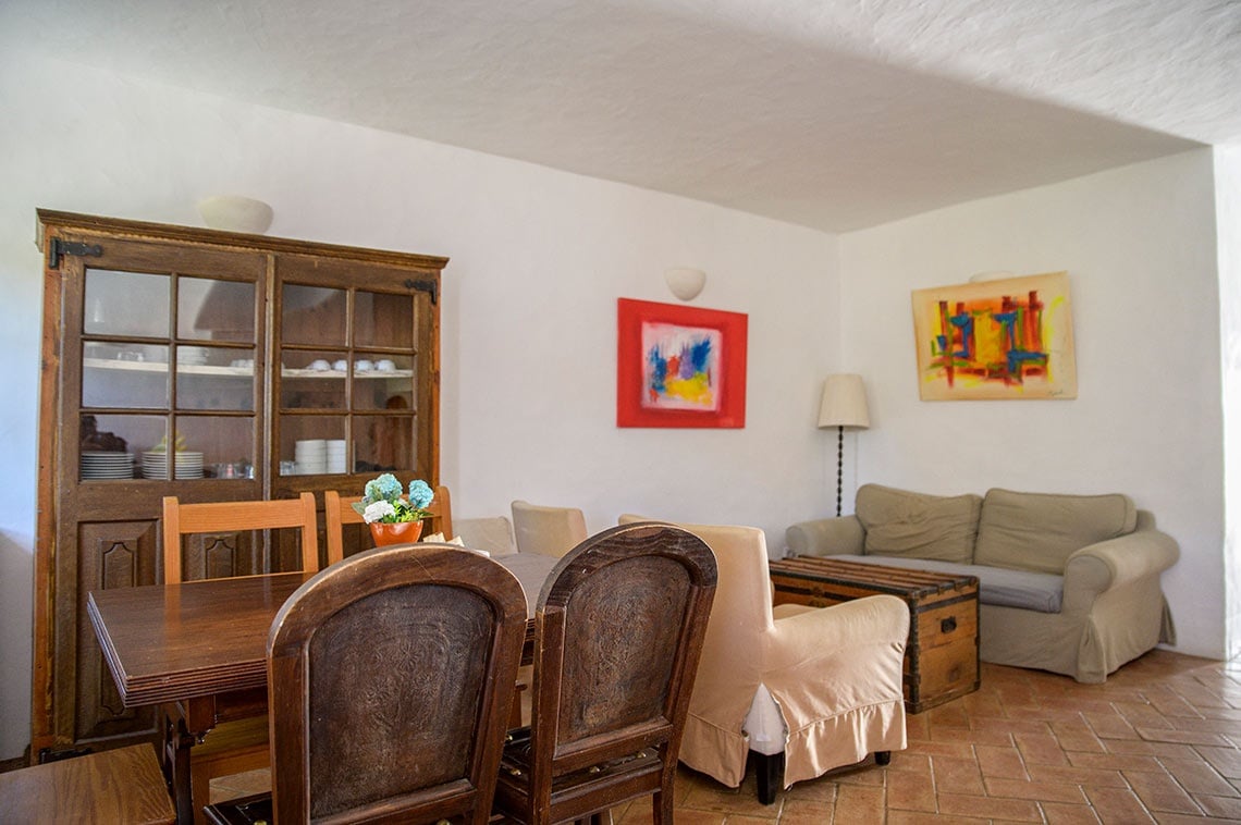 Sala de estar rústica em Aldeia da Pedralva com móveis de madeira e pinturas vibrantes.