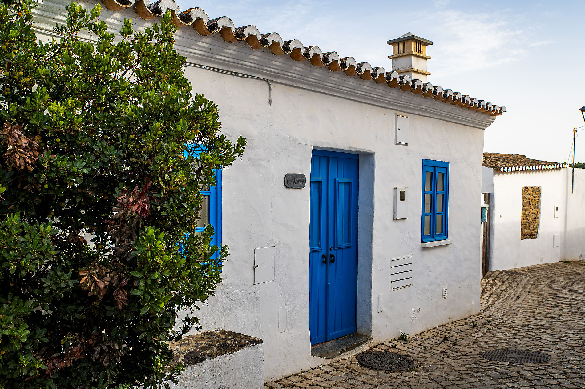 Aldeia da Pedralva: Fachada branca com portas e janelas azuis vibrantes de uma casa pitoresca na Europa.