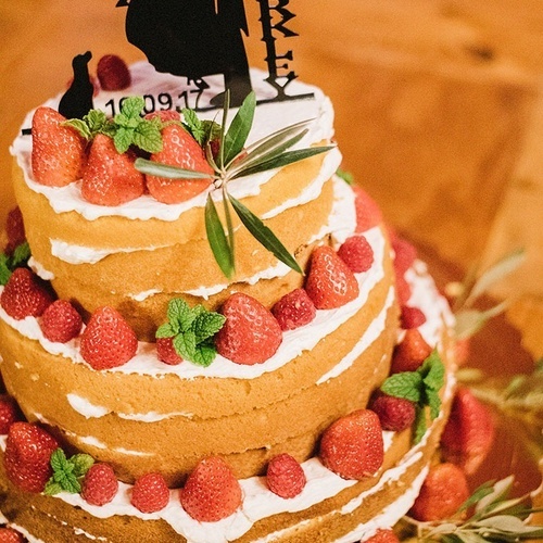 un pastel de bodas con fresas y crema y un topper que dice mr. & mrs.