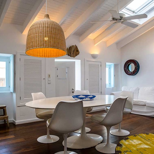 Chic dining area in Aldeia da Pedralva, featuring a rattan pendant light and modern tulip chairs.