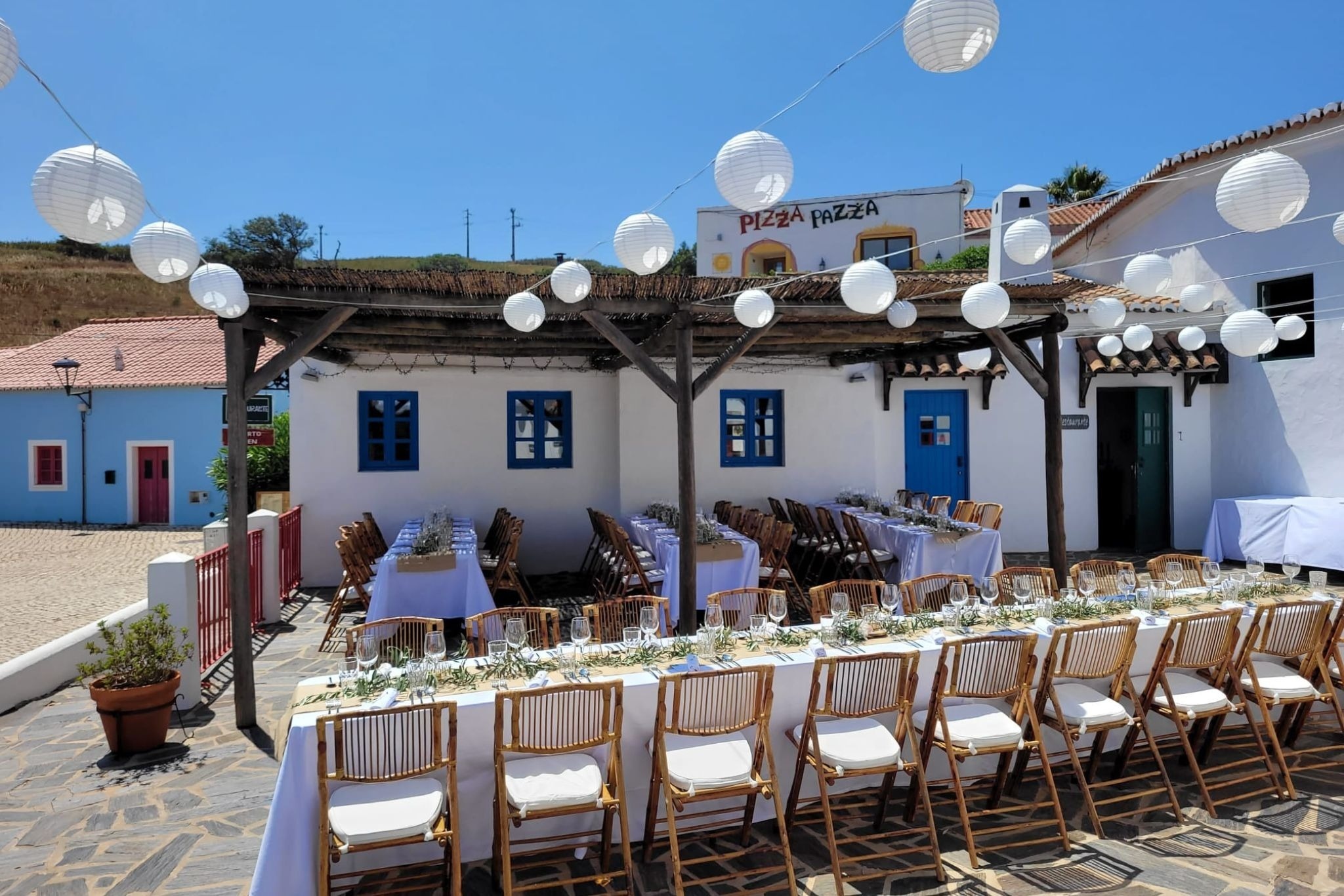 una larga mesa y sillas frente a un restaurante llamado pizza pazza