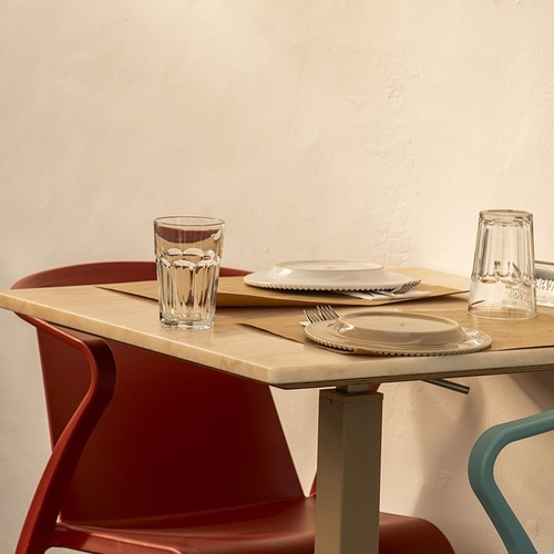 a red chair sits next to a table with plates and glasses on it