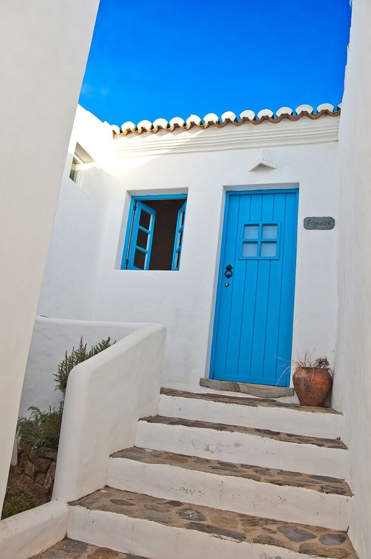 una casa blanca con una puerta azul y una ventana