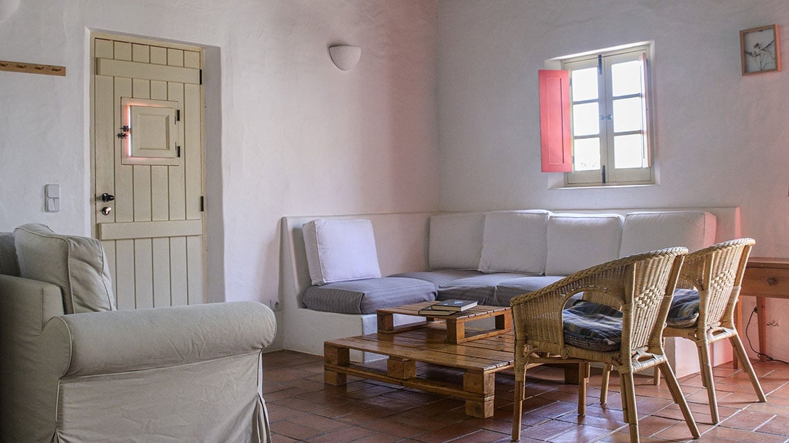 Sala de estar aconchegante na Aldeia da Pedralva, com sofá, poltronas e mesa de centro rústica.