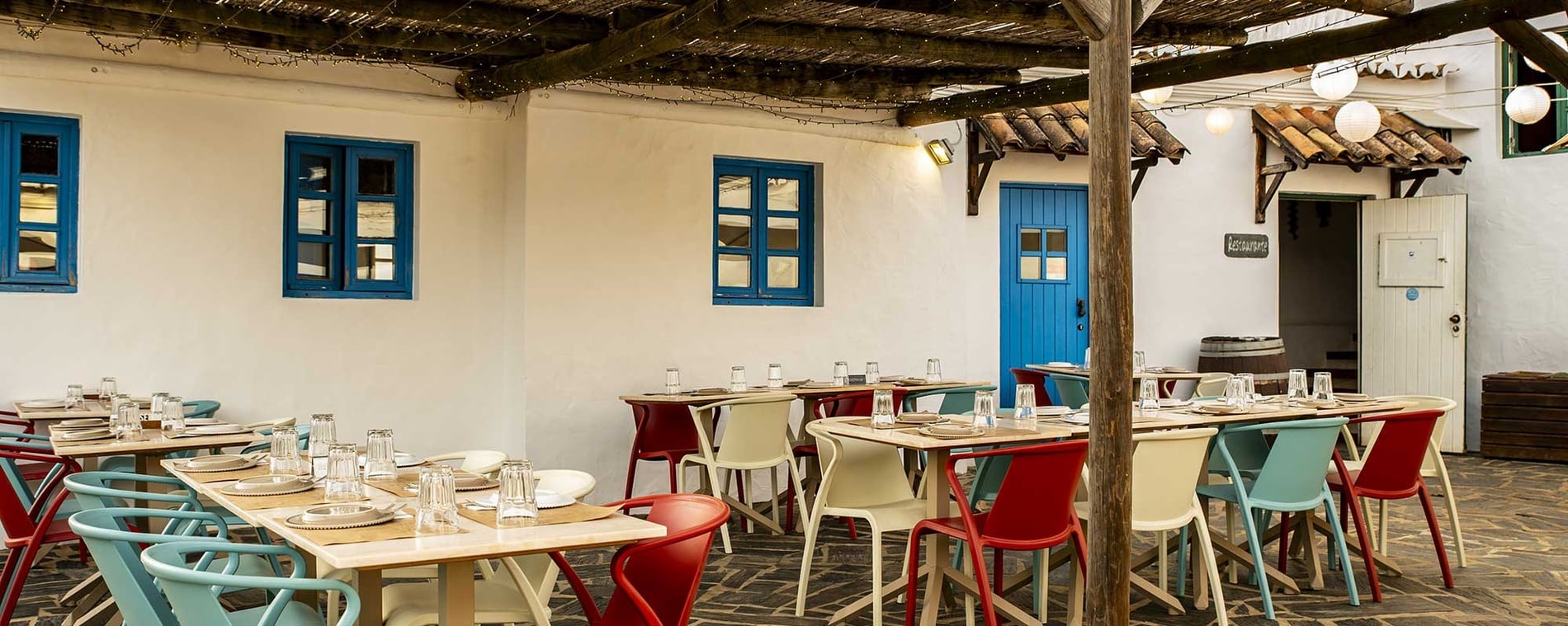 Restaurante na Aldeia da Pedralva, com mesas e cadeiras coloridas e decorações rústicas.