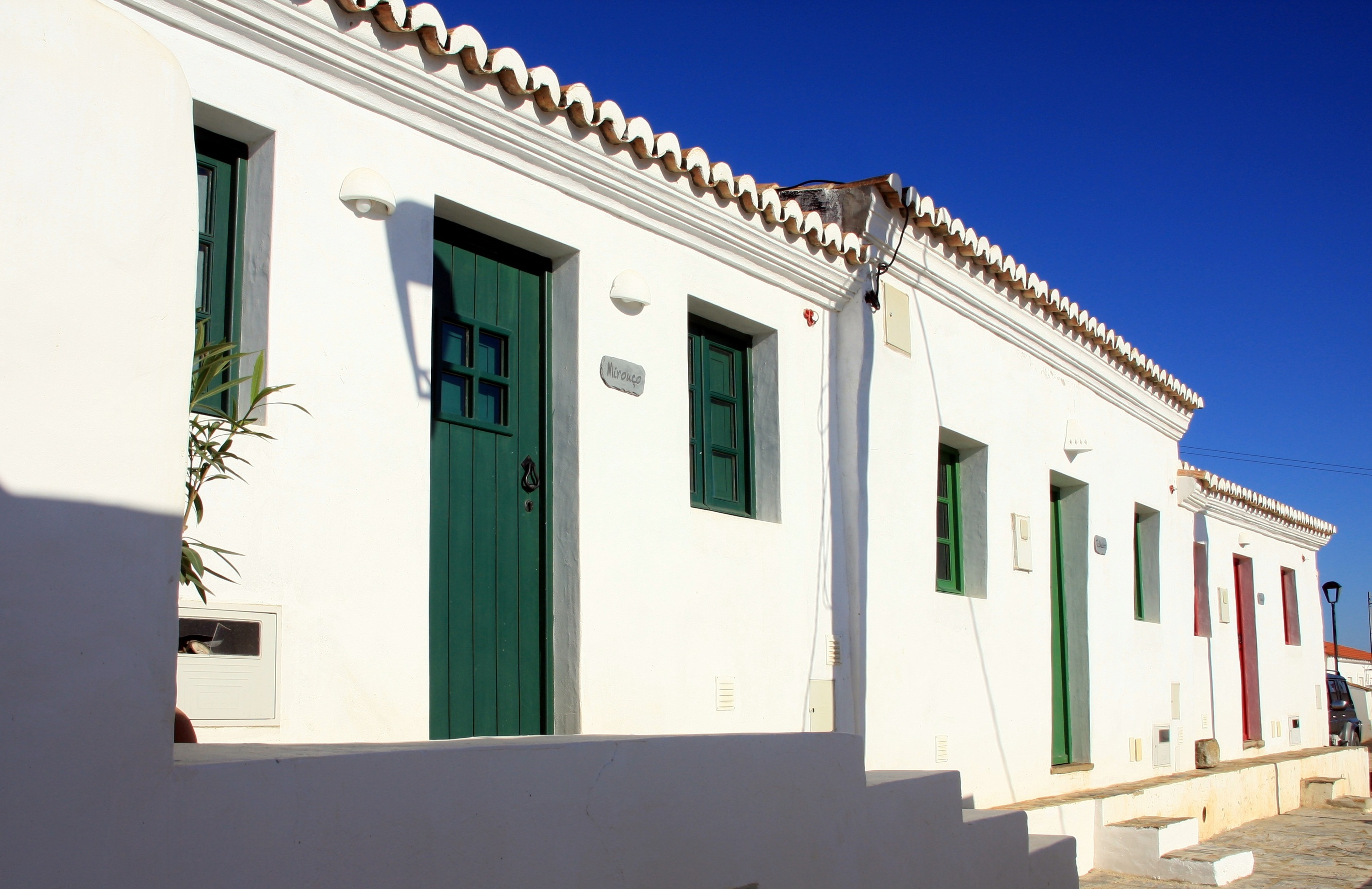 un edificio blanco con puertas verdes y una placa en la pared que dice " avenida "