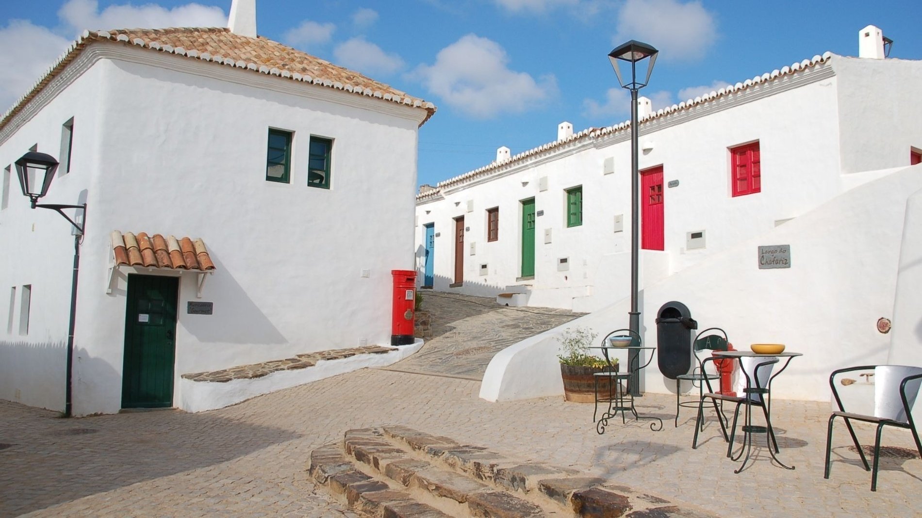 una calle llena de edificios blancos con puertas rojas y verdes