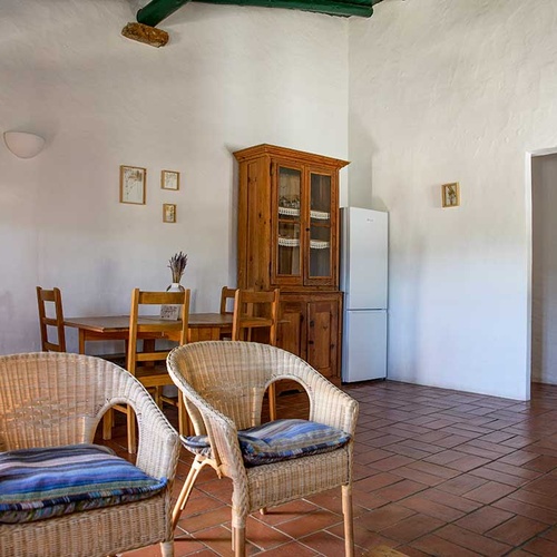 Cozy dining area at Aldeia da Pedralva with wicker chairs and rustic wooden furniture.