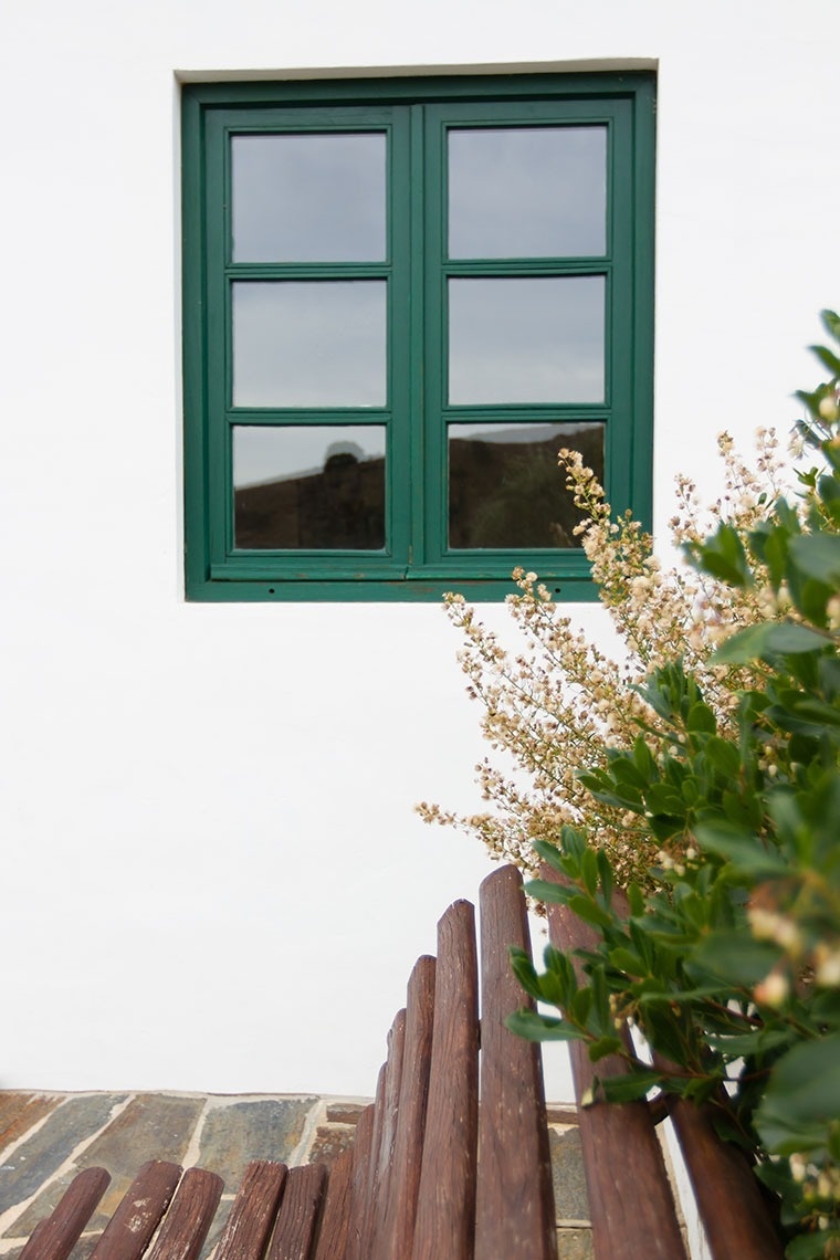 un banco de madera frente a una ventana verde