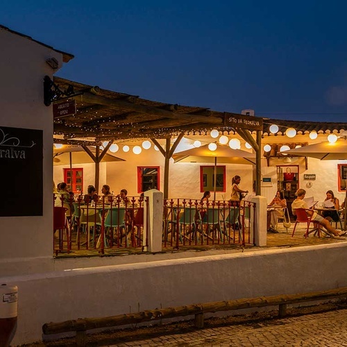 Evening view of Sítio da Pedralva restaurant in Aldeia da Pedralva, Portugal, with outdoor seating and lights.