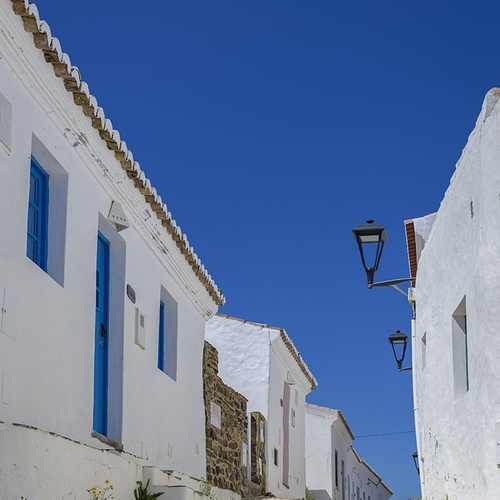a cobblestone street with white buildings and blue doors
