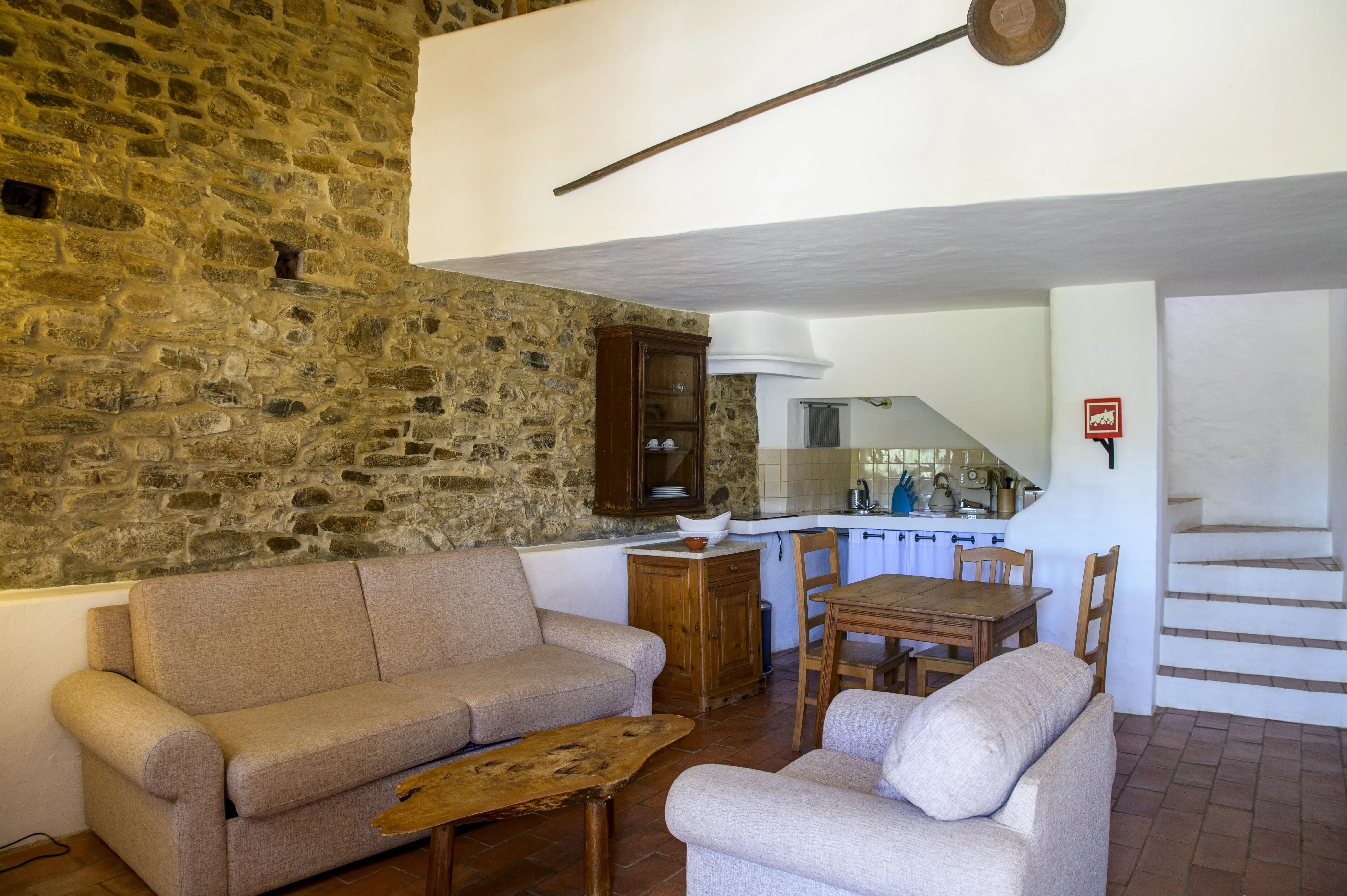 Cozy living area with stone walls, sofas, dining table, and kitchen Aldeia da Pedralva - Slow Village.
