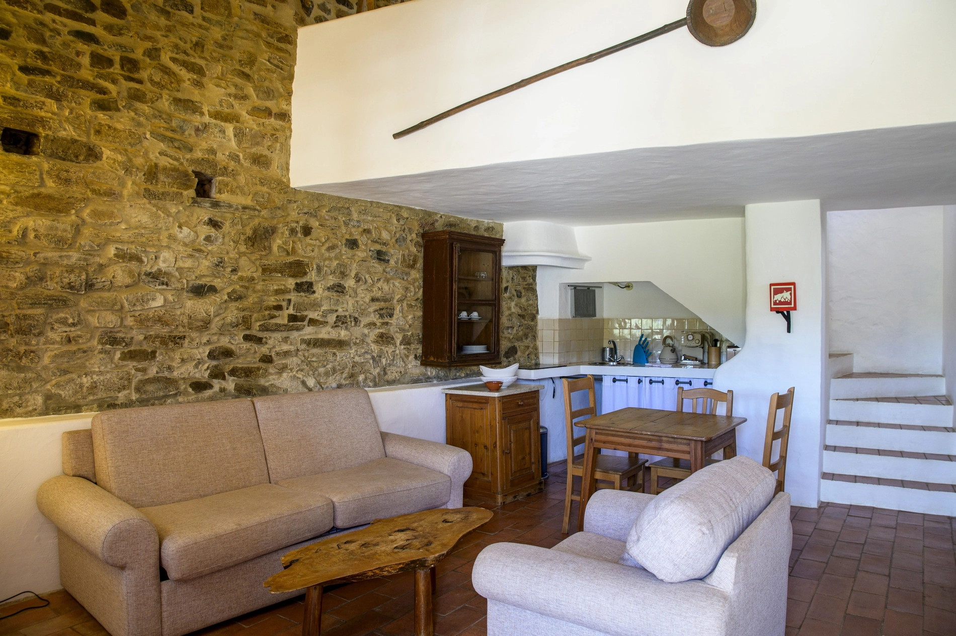 Cozy living area with stone walls, sofas, dining table, and kitchen Aldeia da Pedralva - Slow Village.