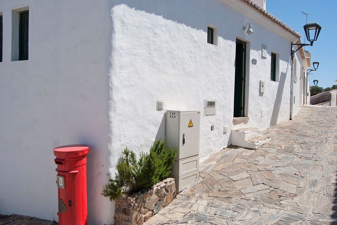 un buzón rojo está al lado de una pared blanca