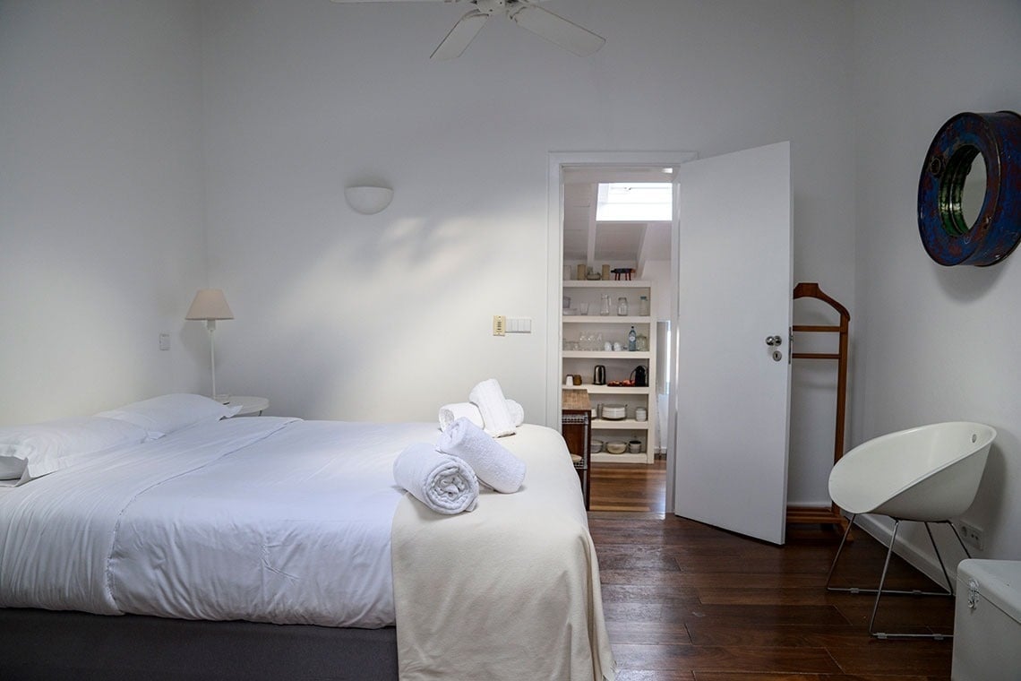 una habitación blanca con una cama y un ventilador de techo