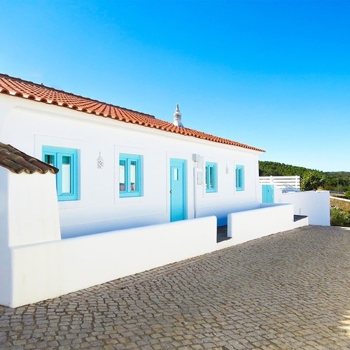 una casa blanca con una puerta azul y ventanas azules