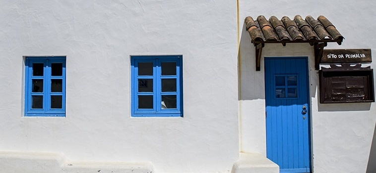 uma casa branca com janelas azuis e uma porta azul