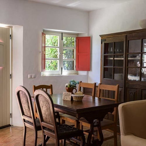 Charming dining room in Aldeia da Pedralva with wooden table, chairs, and antique cabinet.
