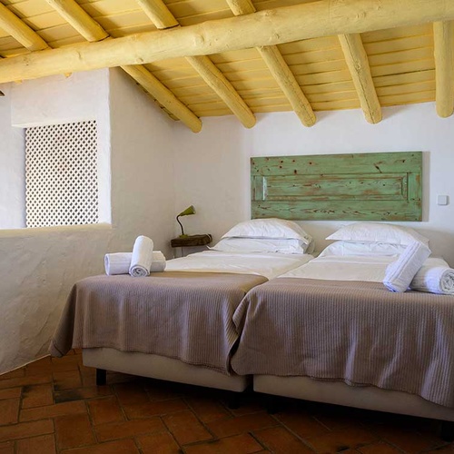 Aldeia da Pedralva charming twin beds with white linens and rustic green headboard.