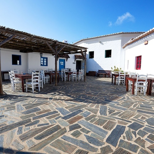 un patio con mesas y sillas frente a un edificio blanco