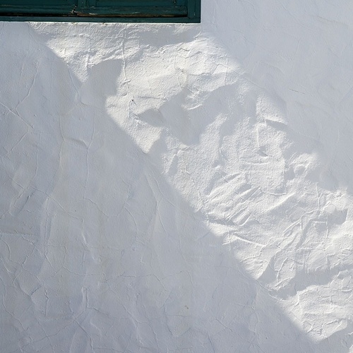 a green window casts a shadow on a white wall