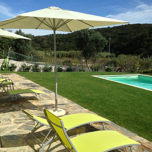 a swimming pool surrounded by lawn chairs and umbrellas