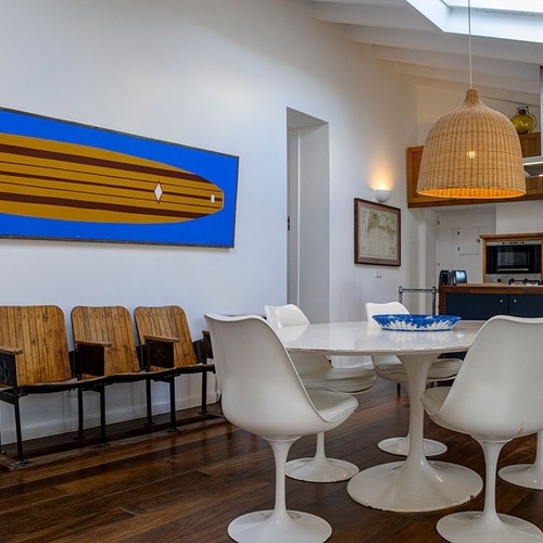 a dining room with a table and chairs and a painting of a surfboard on the wall