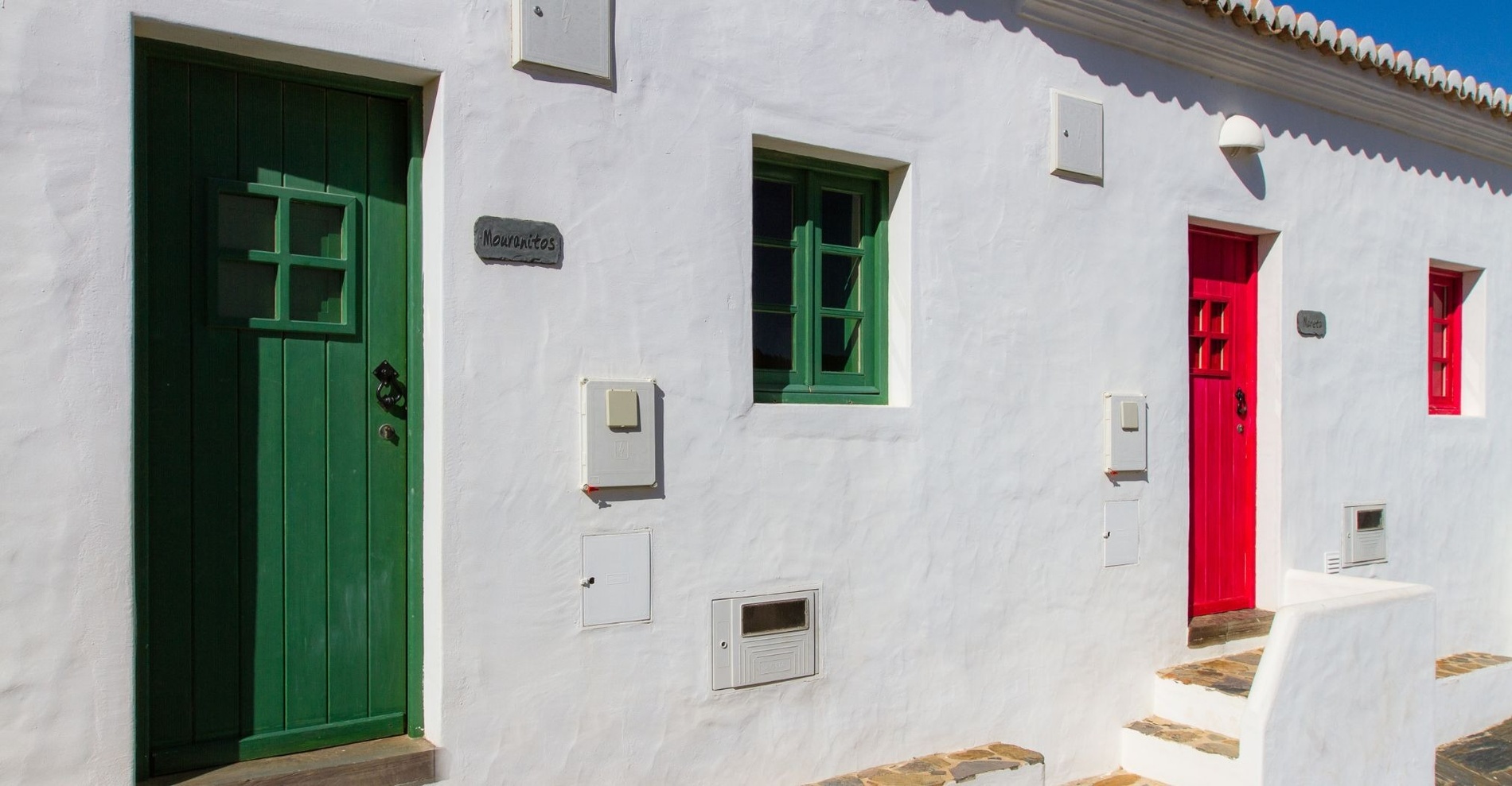 una casa blanca con puertas verdes y rojas