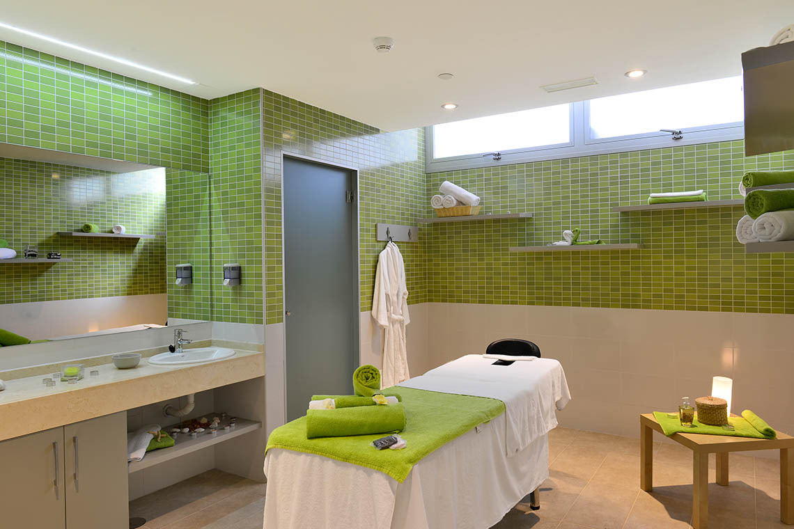 Heller Spa-Massageraum im Alexandre Corporativa mit grünen Mosaikfliesen, Buddha und Entspannungsliege.