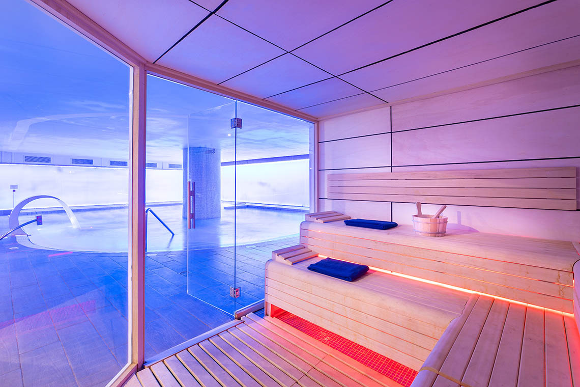 Spa relajante con dos camillas, luces colgantes y espejo iluminado en Alexandre Corporativa.