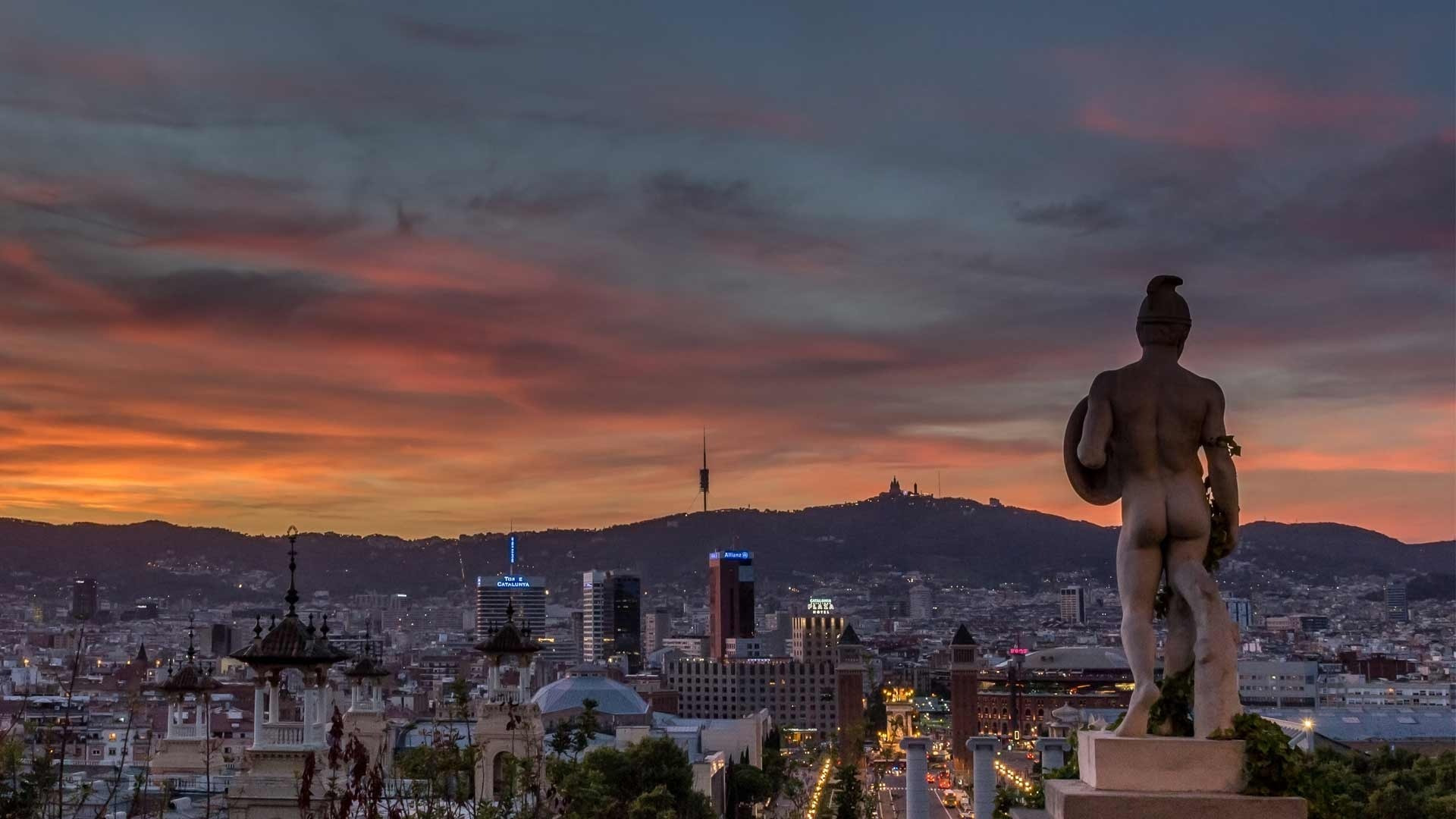 Stunning Barcelona sunset panorama with city lights, mountains, and the Alexandre Plaza hotel.